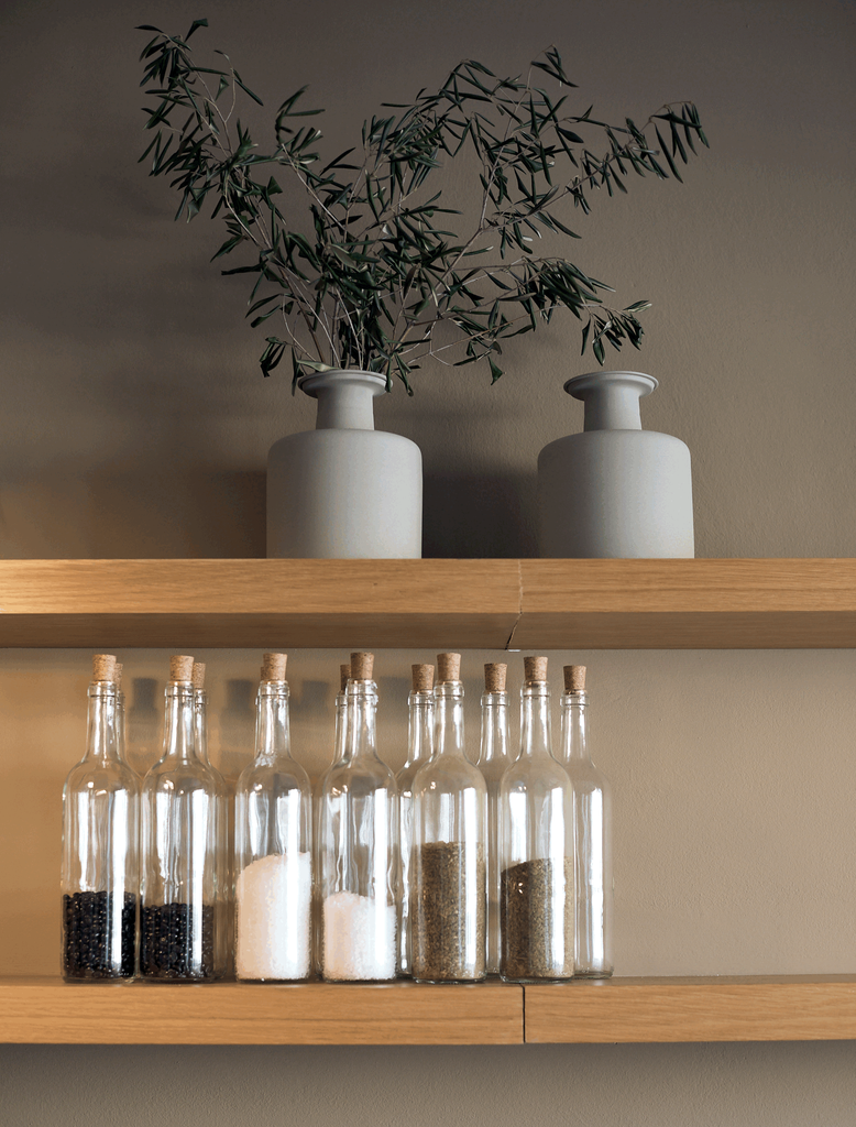 a shelf with bottles and a plant on it. A vase with olive tree branches, Sklum home decoration, glass wine bottle decoration, rustic shelves. Organic home staging. Interior design, Interior decoration by Aptó interiors in Barcelona 