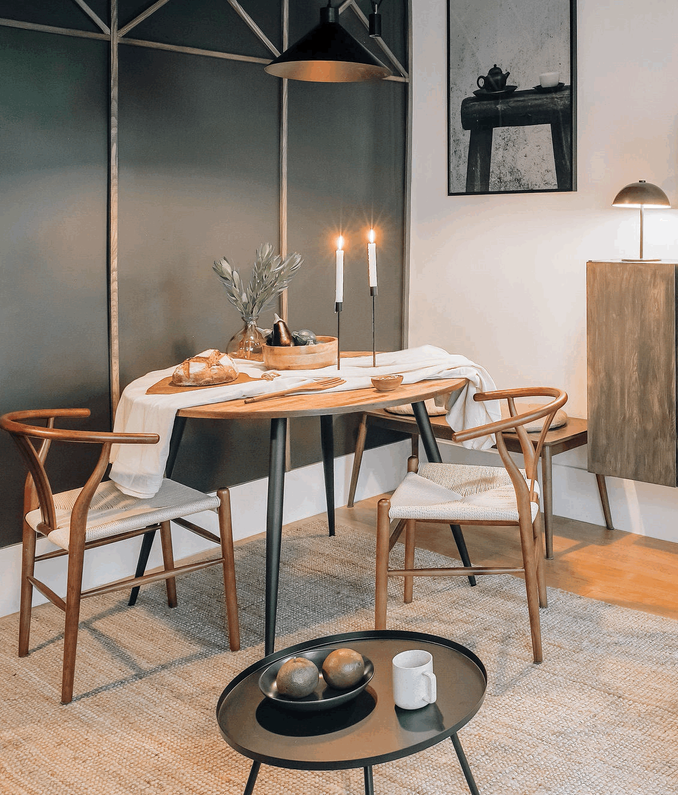 a dining table and chairs in a room in a Paris Apartment design. Black and white picture in frame, wall decoration, minimalist and cozy dining room, Ivar Ikea, round metal side table, wishbone chairs sklum, round table, bench table. Aptó interiors