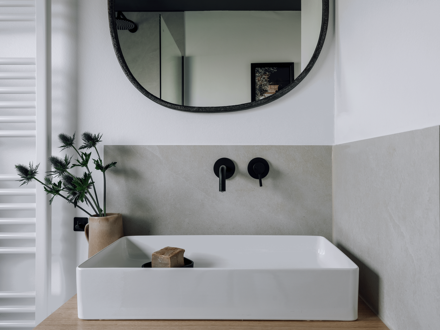 a modern bathroom with a sink and mirror. Organic shaped mirror, black water tap, bathroom design, bathroom setting, Aleppo soap, beige bathroom, cozy bathroom design by Aptó interiors Kelly Wearstler, VT wonen