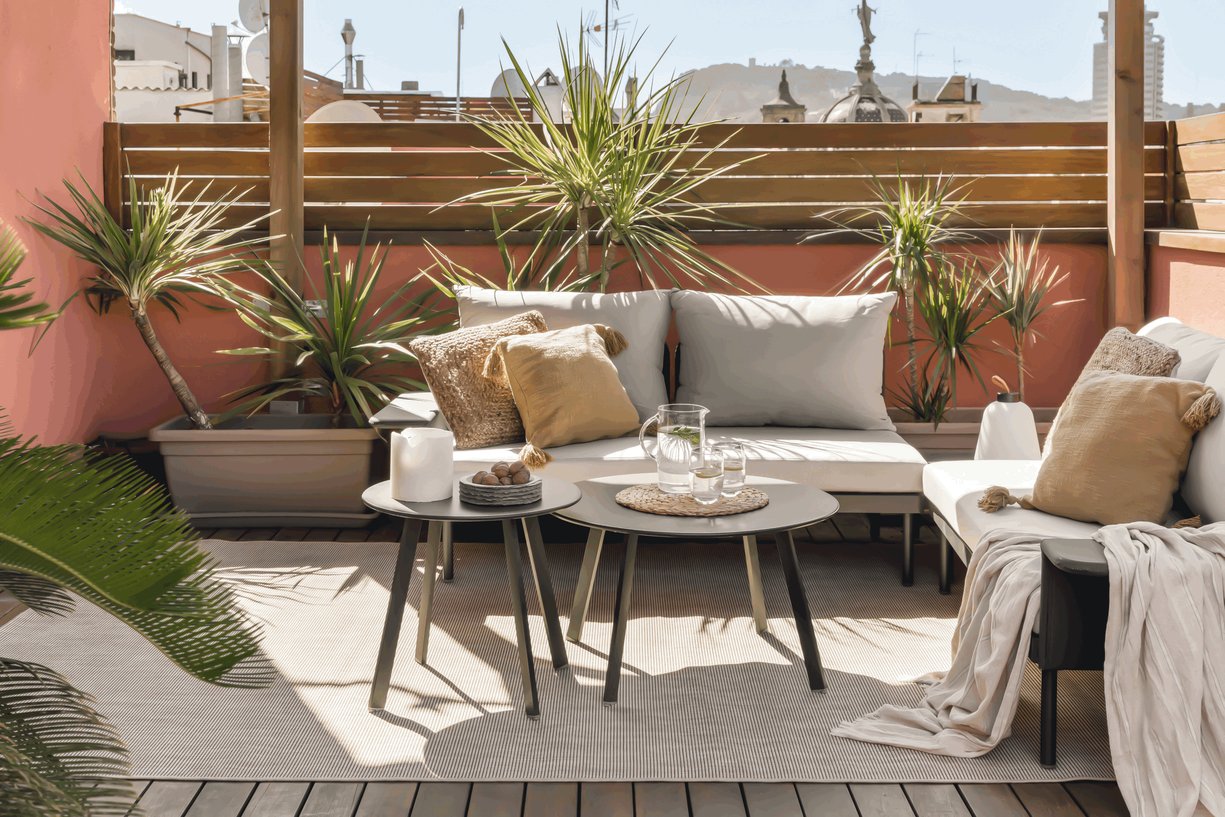 a balcony with white furniture and potted plants. Barcelona terrace design with big lounge set, plants on terrace, terrace jungle, terracotta walls, have home, zara home design, outside rugs, by Aptó interiors VT Wonen, Apartment Magazine 